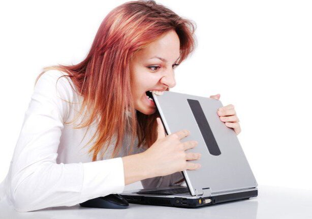 crazy-young-woman-is-biting-her-laptop-in-office_rtg8xNA4i