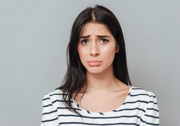 graphicstock-portrait-of-sad-young-woman-standing-over-grey-background-look-at-camera_rLoPXKmd2x-1
